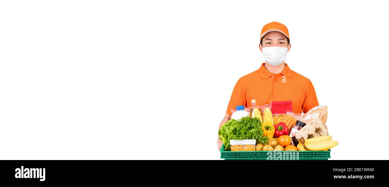 Un homme de livraison de supermarché portant un masque médical tout en tenant des aliments et des paniers d'épicerie isolés sur fond de bannière blanche avec espace de copie Banque D'Images