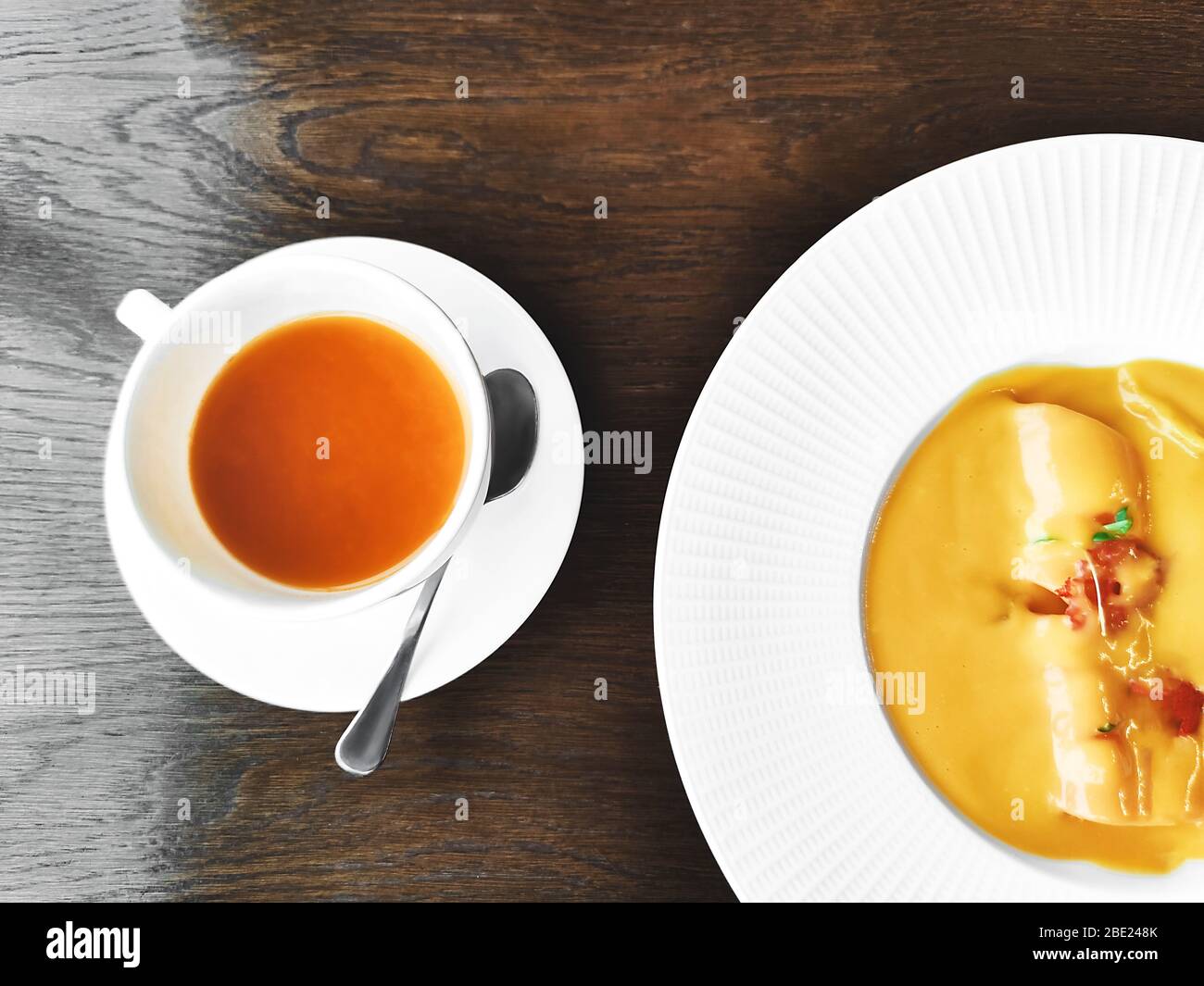 Tasse de thé aux herbes saines avec buckthorn, gingembre et miel et soupe à la crème de citrouille sur une table en bois clair texturé dans un café moderne branché Banque D'Images