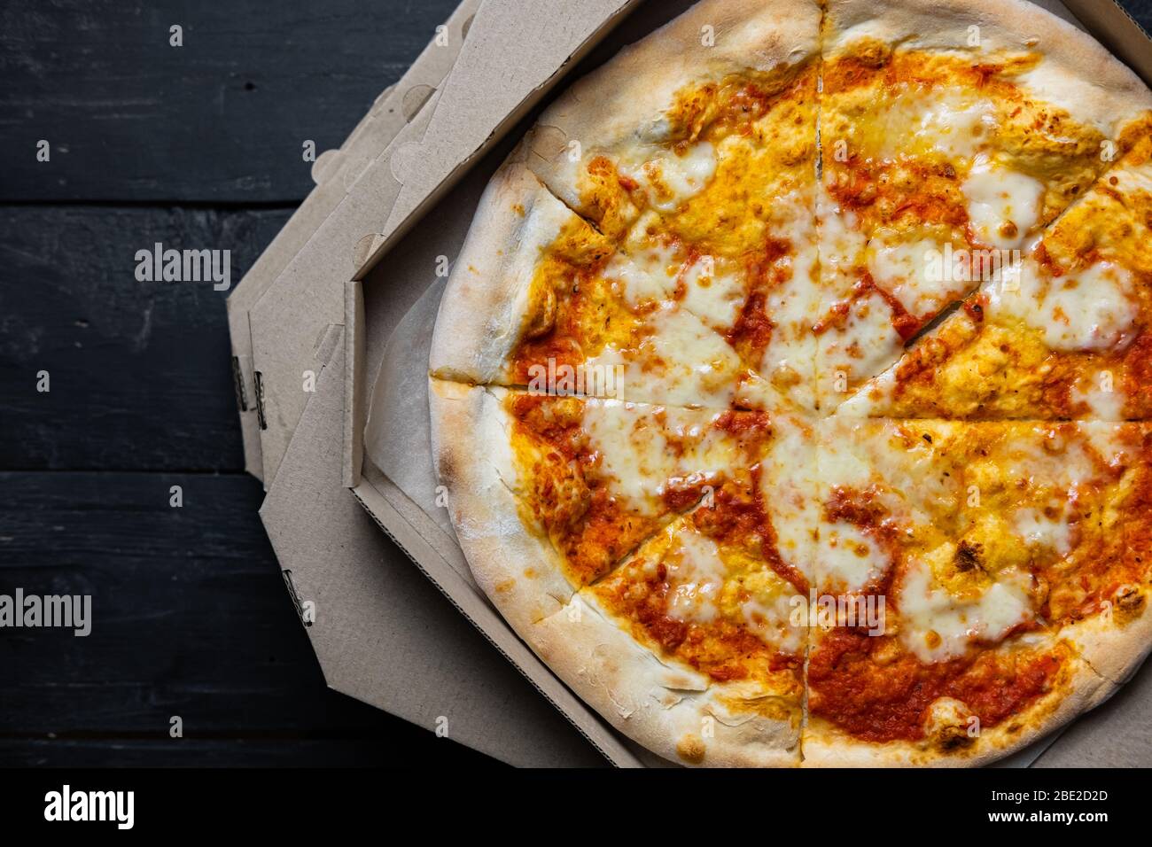 Pizza margherita dans une boîte de livraison ouverte, image à faible clé. Livraison des aliments, concept de nourriture à emporter: Pile de boîtes à pizza sur fond de bois noir Banque D'Images Pizza margherita dans une boîte de livraison ouverte, image à faible clé. Livraison des aliments, concept de nourriture à emporter: Pile de boîtes à pizza sur fond de bois noir Banque D'Images