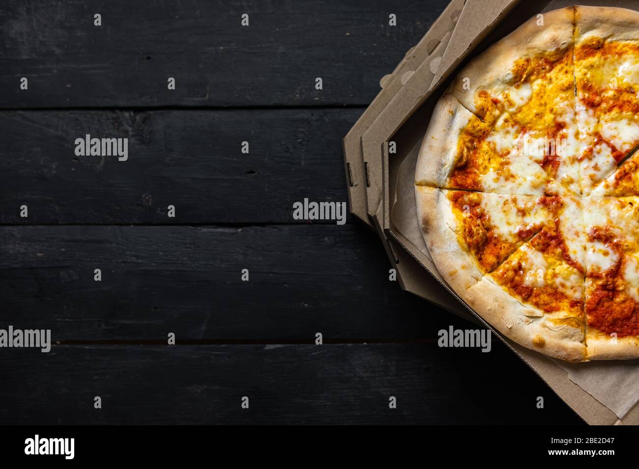 Pizza margherita dans une boîte de livraison ouverte, fond sombre avec espace texte. Livraison des aliments, concept de nourriture à emporter: Pile de boîtes à pizza sur le dos en bois noir Banque D'Images Pizza margherita dans une boîte de livraison ouverte, fond sombre avec espace texte. Livraison des aliments, concept de nourriture à emporter: Pile de boîtes à pizza sur le dos en bois noir Banque D'Images