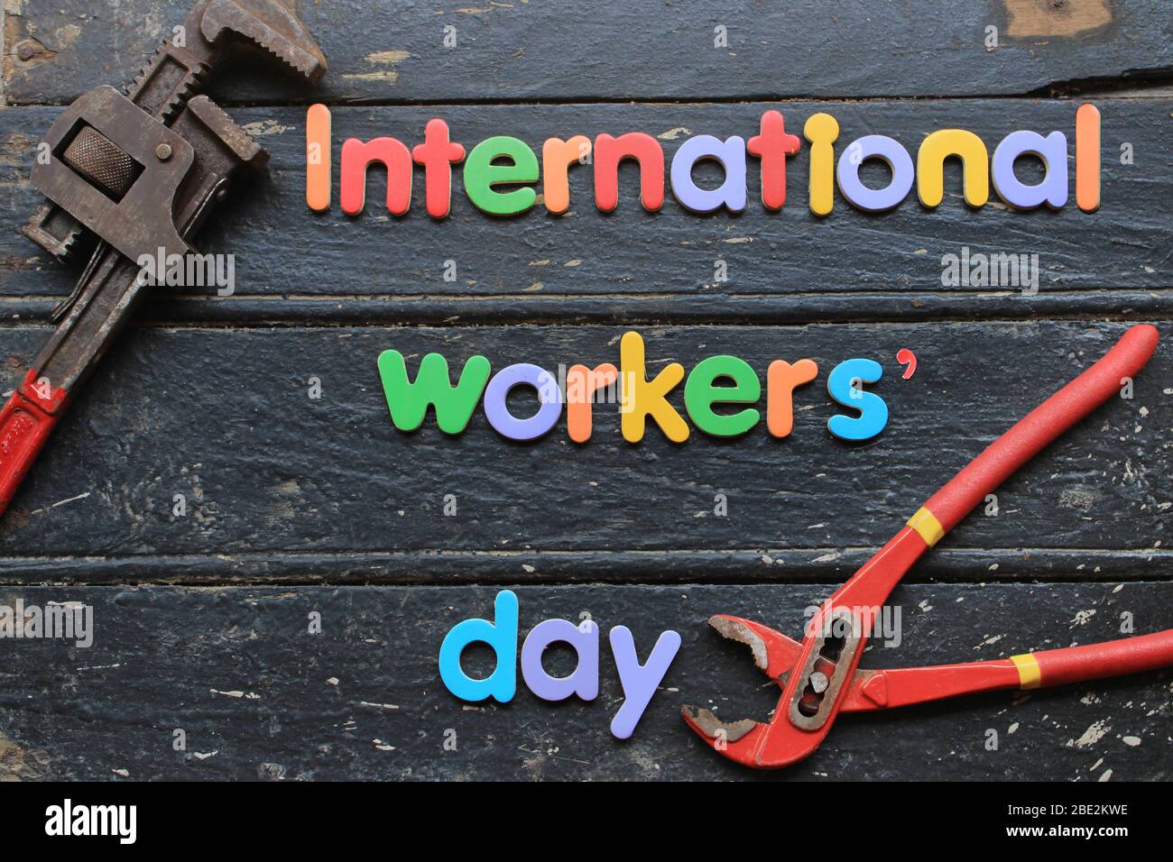 Texte international de la journée du travail en rouge sur fond de bois avec outils de réparation de construction. Signe concept de la journée du travail. Journée internationale des travailleurs. Banque D'Images