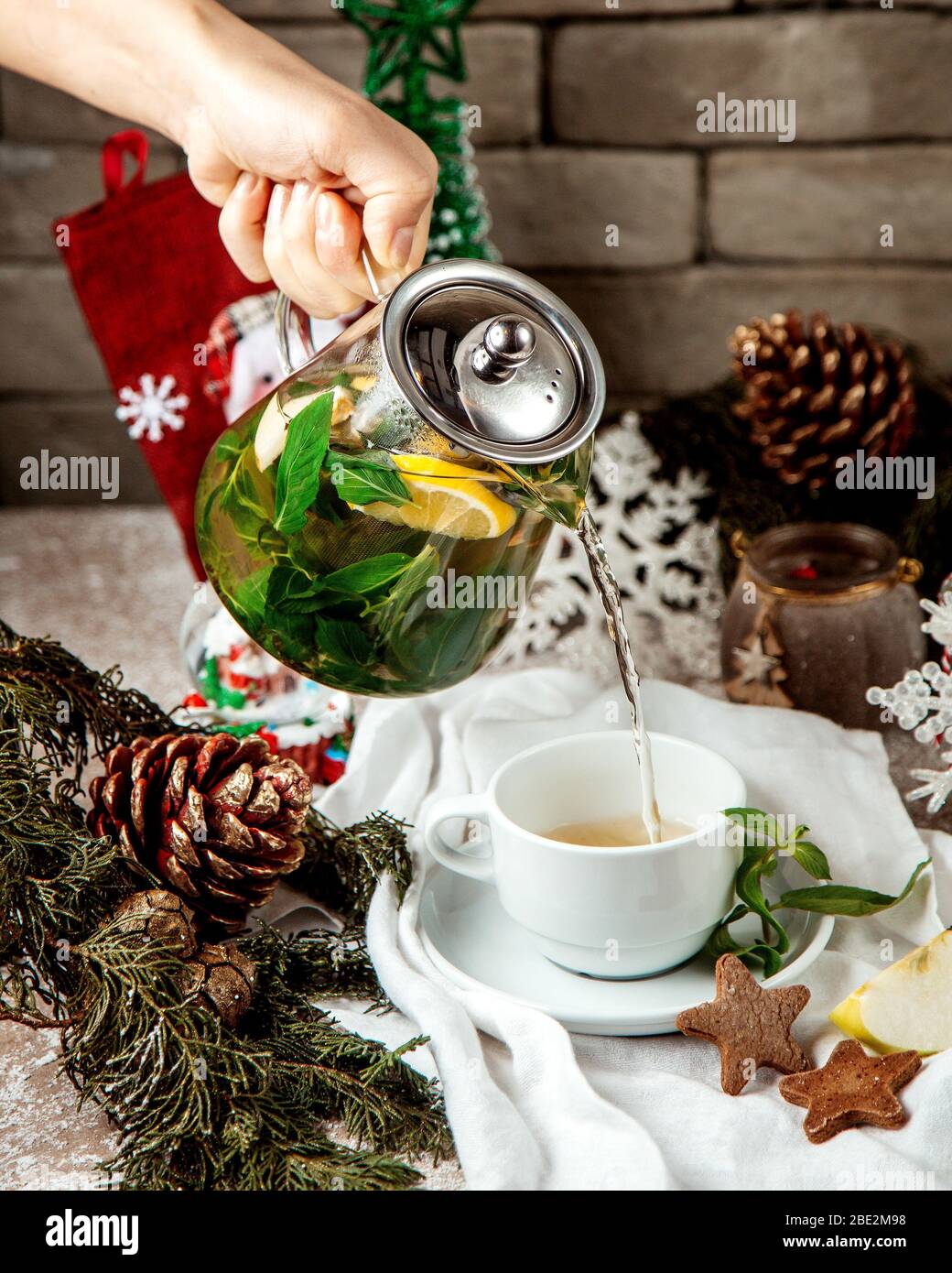 femme qui verse du thé au gingembre avec de la menthe, laissez le citron et le miel dans la tasse Banque D'Images