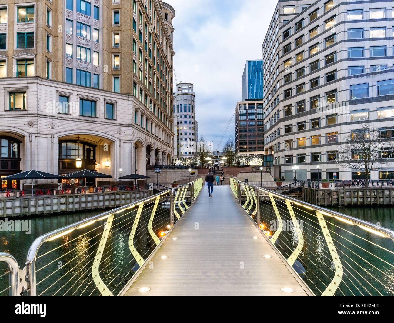 Place de l'Inde et place Cabot unis par un pont de sentier illuminé au crépuscule près de Canary Wharf à Londres. Banque D'Images