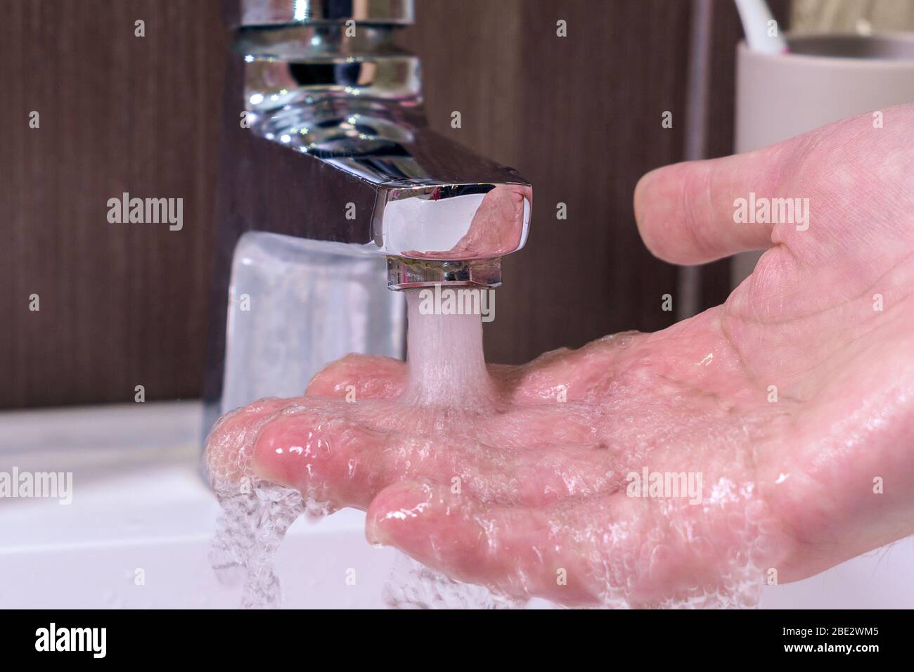 contrôle de la température en touchant l'eau courante avec la main. Gros  plan sur les doigts sous l'eau chaude du robinet ou de la baignoire dans la  salle de bains A Photo
