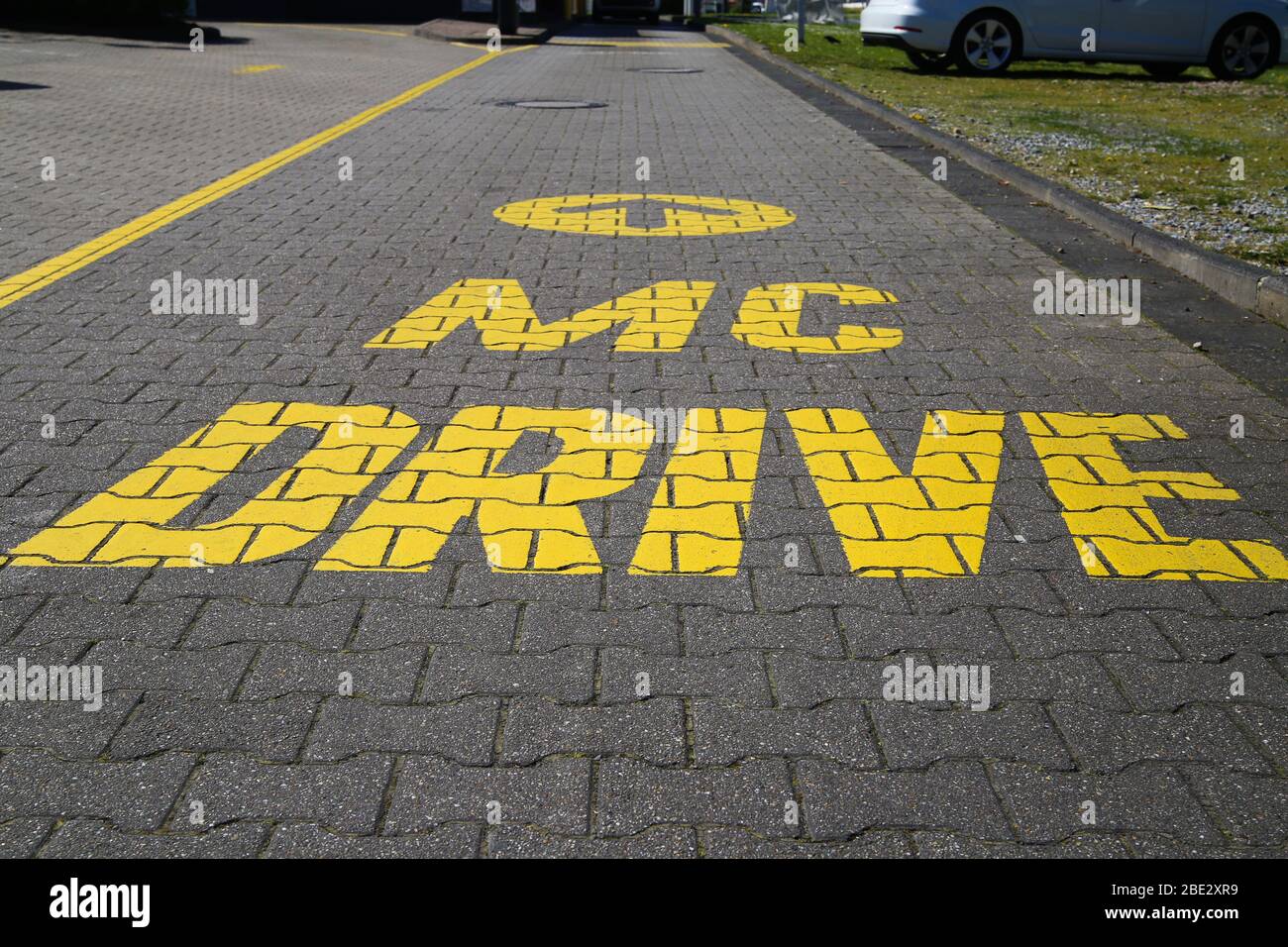Mönchengladbach, Allemagne - 9 avril. 2020: Vue sur la conduite isolée de McDonald's dans l'entrée mcdrive peint en jaune sur le sol Banque D'Images