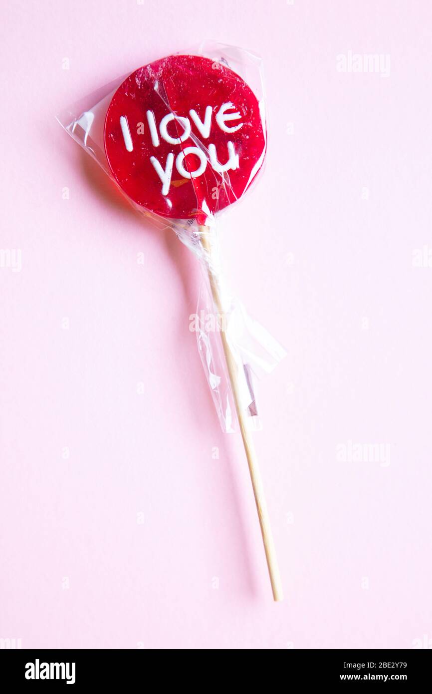 Un doux enroulée rouge « Je t'aime » sur fond rose pastel, plat, vue sur le dessus, minimaliste Banque D'Images