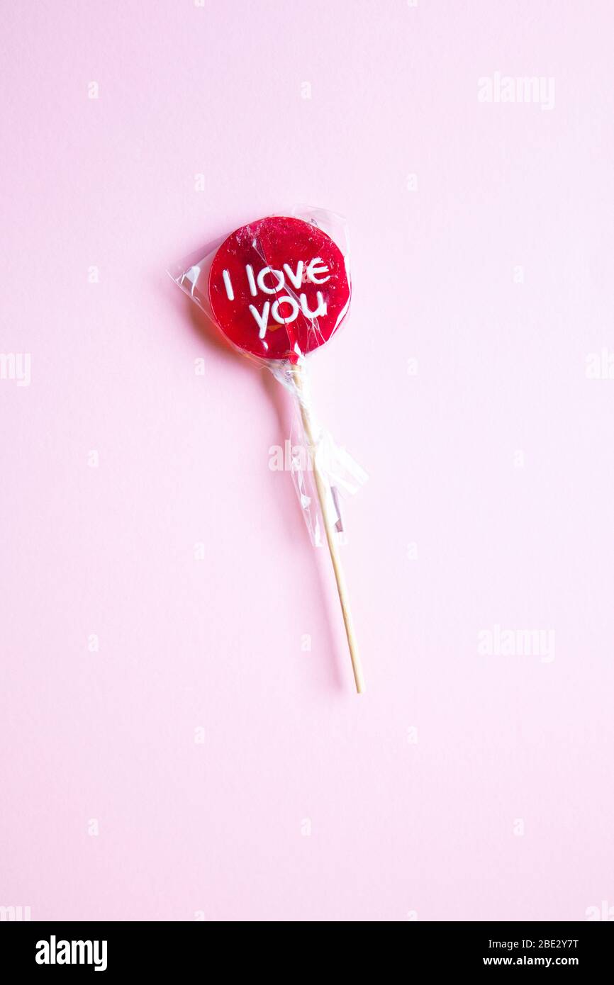 Un doux enroulée rouge « Je t'aime » sur fond rose pastel, plat, vue sur le dessus, minimaliste Banque D'Images