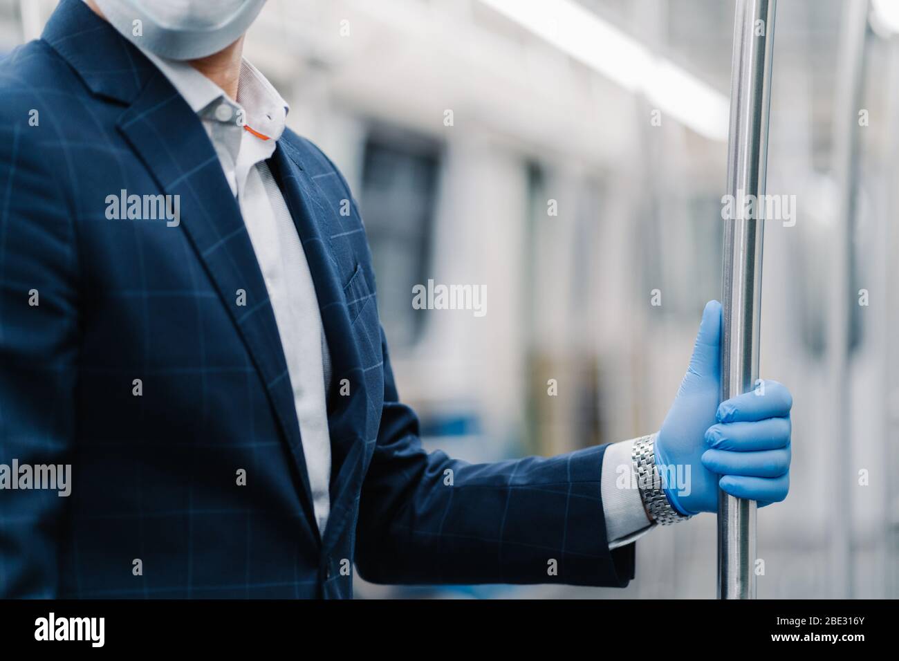 Le passager de l'homme porte un gant médical protecteur du coronavirus, touche la main courante dans le chariot de métro, pose dans les transports publics, habillés officiellement. Virus Banque D'Images