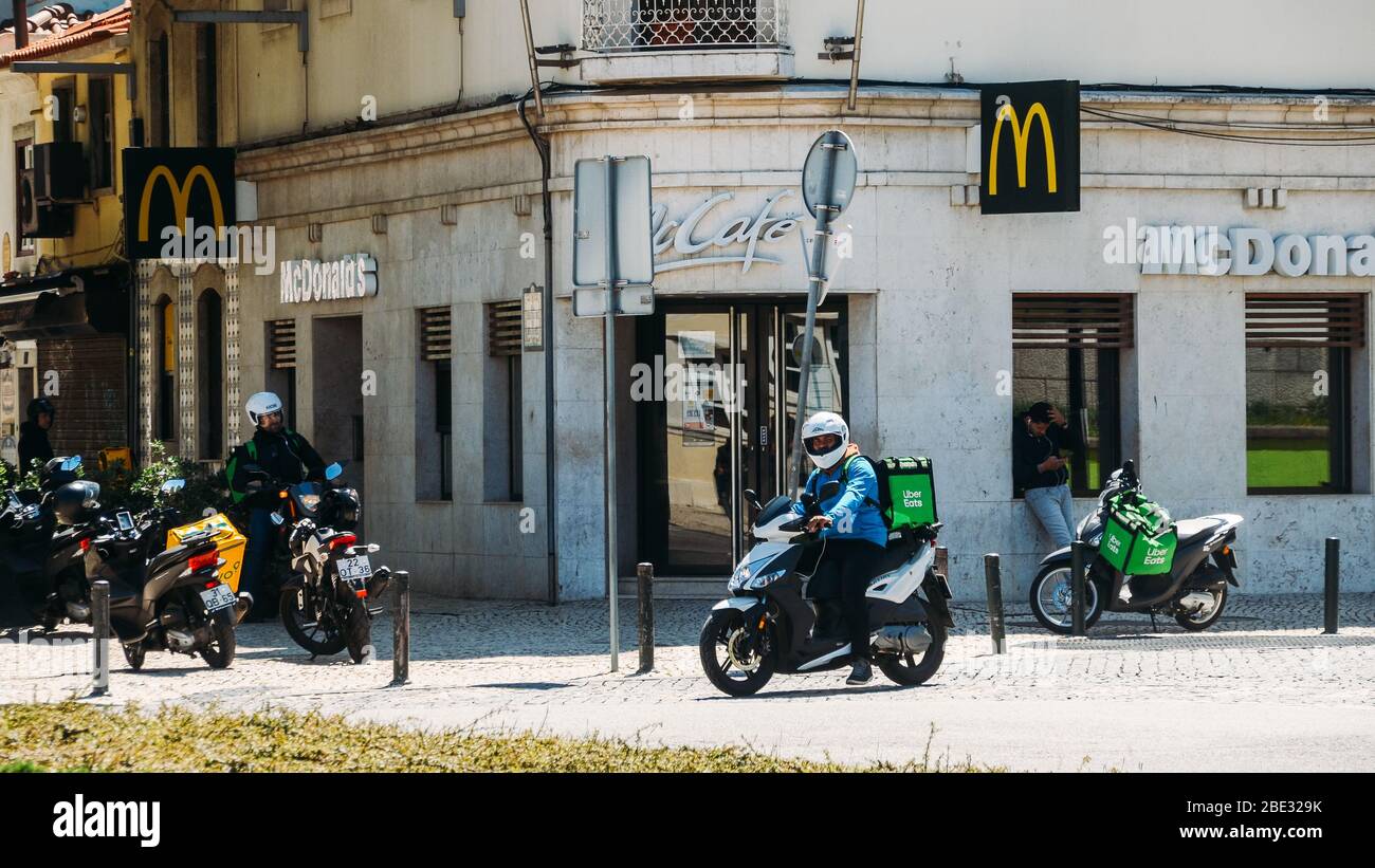 Cascais, Portugal - 11 avril 2020: Glovo et UberEats livrant des coursiers sur la moto devant un restaurant McDonalds pendant le Coronavirus Covid- Banque D'Images