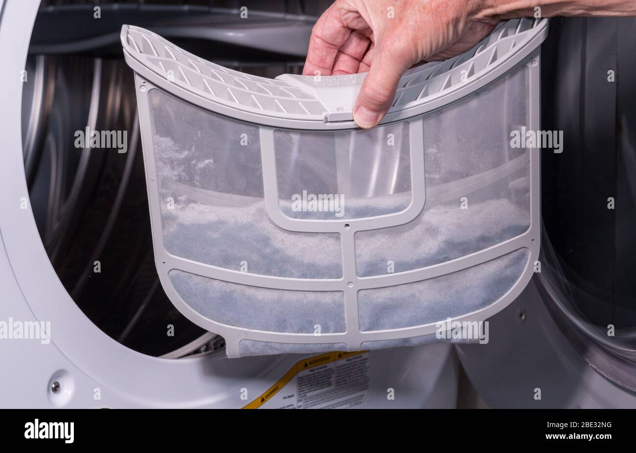 Homme caucasien senior tenant le piège rempli de peluches d'un sèche-linge à chargement frontal Banque D'Images