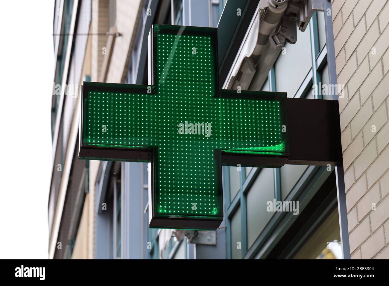 Enseigne pharmacie située dans le centre-ville de Zürich, Suisse. La croix verte avec lumière est un symbole universellement connu pour l'industrie pharmaceutique. Banque D'Images