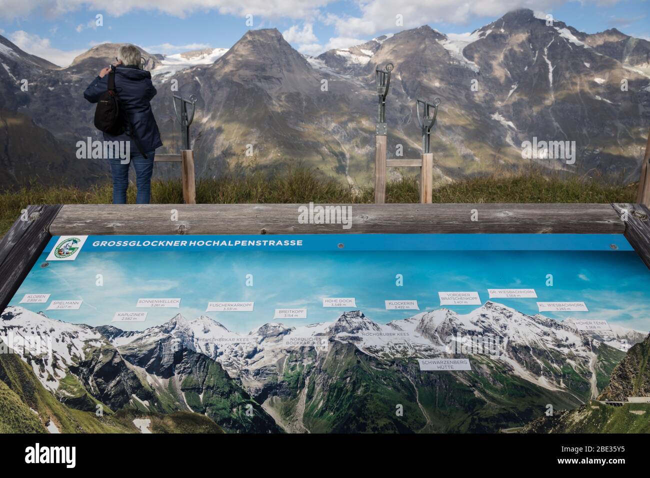 Carte touristique panoramique détaillant les sommets de montagne de la Grossglockner Hochalpenstrasse en premier plan, tandis qu'une femme voit les pics réels en t Banque D'Images