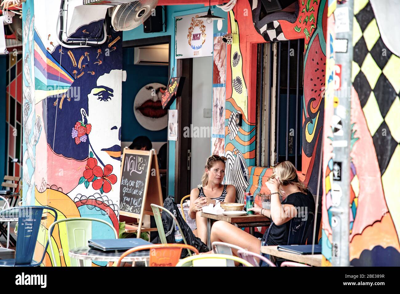 Deux filles ayant une pause déjeuner à Haji Lane, Singapour. Dos mujeres en su pausa para la comida en Haji Lane, Singapur Banque D'Images