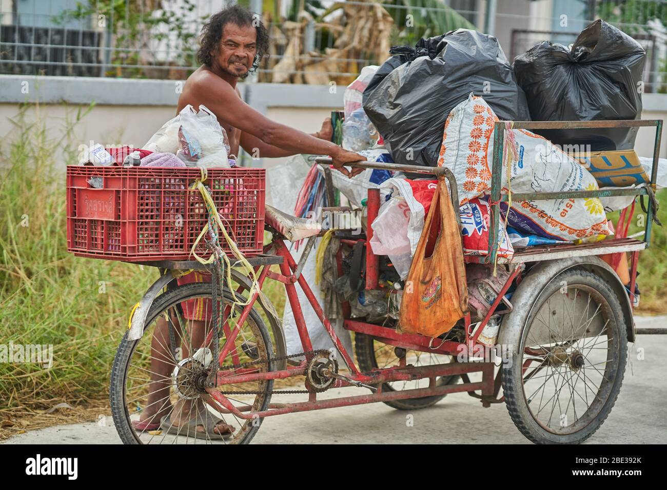 Un homme collecte des matériaux de recyclage sur une route rurale en Thaïlande. Banque D'Images