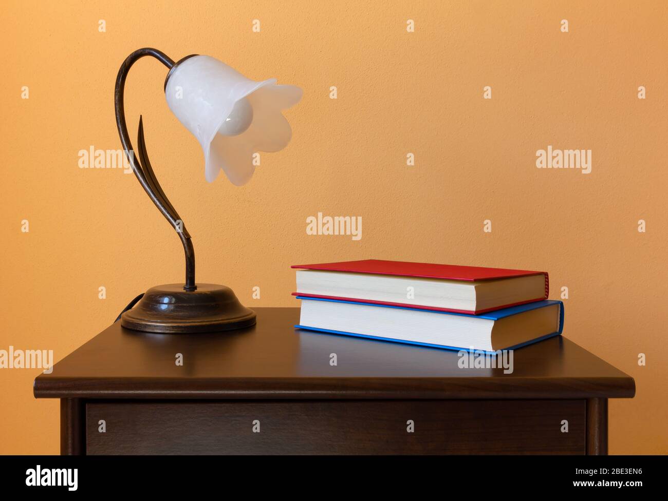 Une lampe classique en forme de fleur et deux livres sur une table de nuit en bois Banque D'Images