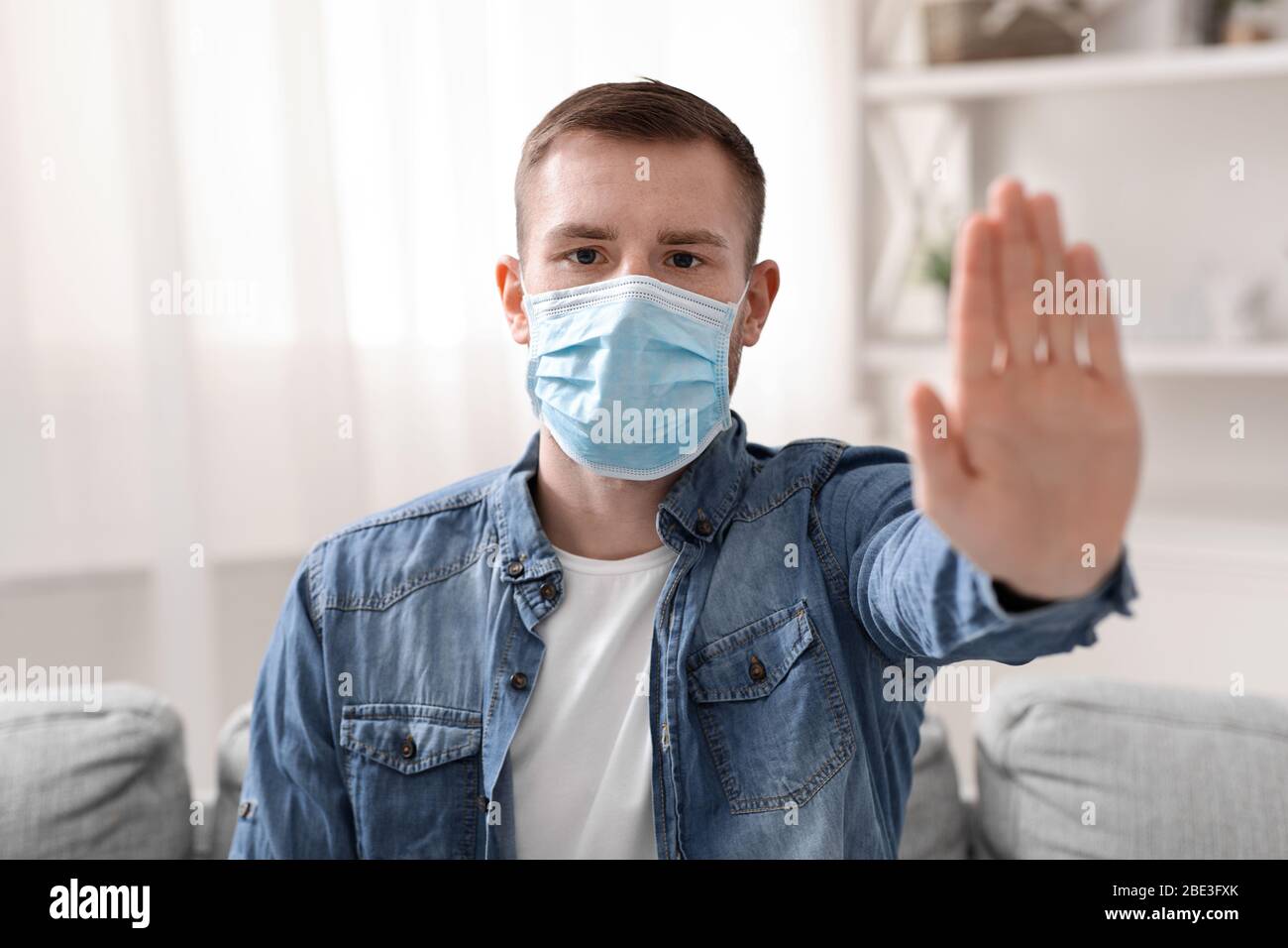 Jeune homme dans le masque de protection s'arrête de gestuelle sur l'appareil photo Banque D'Images