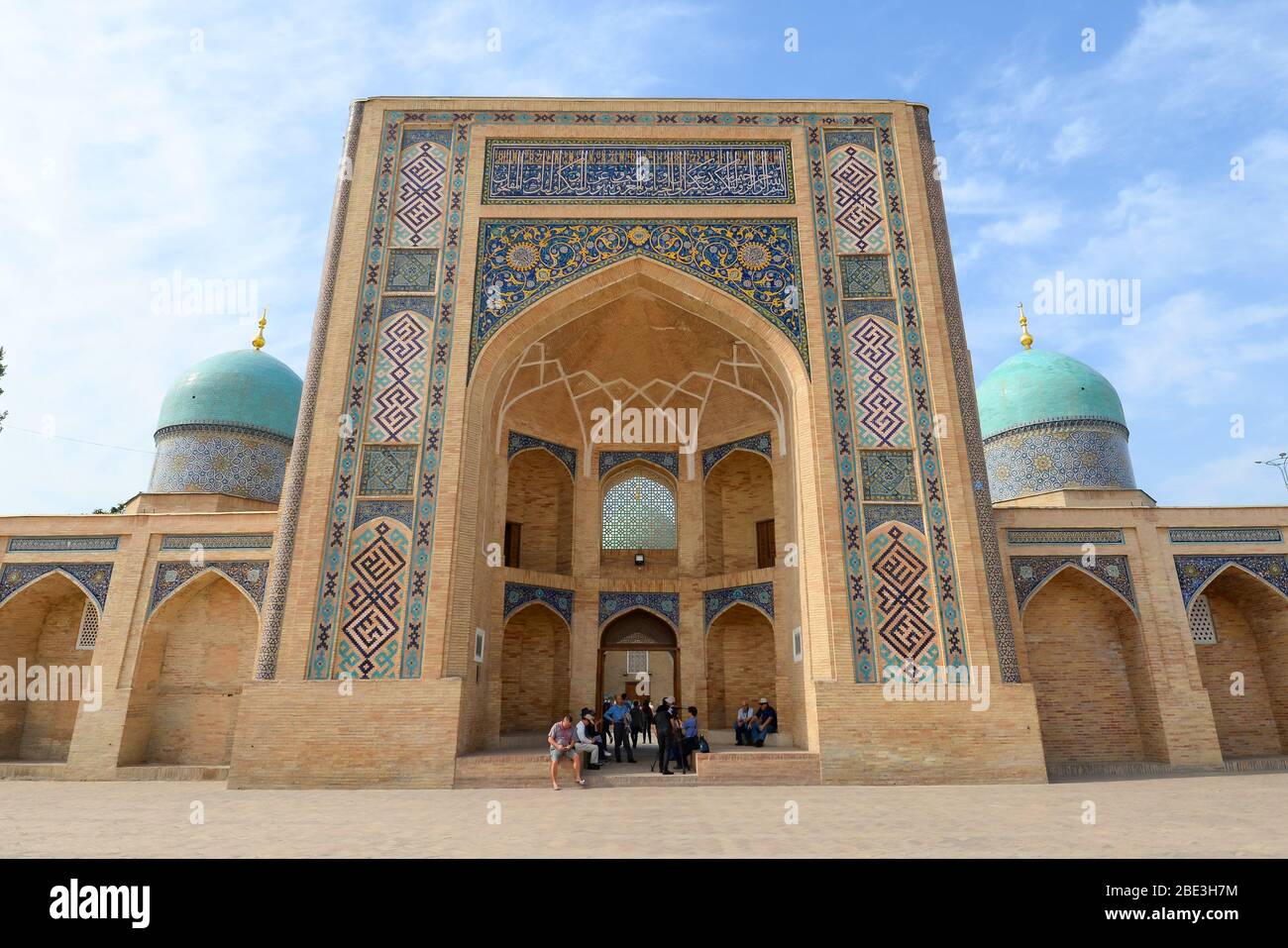 Vue frontale de la façade de Barakhan Madrasah à Tachkent, Ouzbékistan. Groupe de touristes assis se cachant de la chaleur et du soleil en Asie centrale. Barakh-khan. Banque D'Images