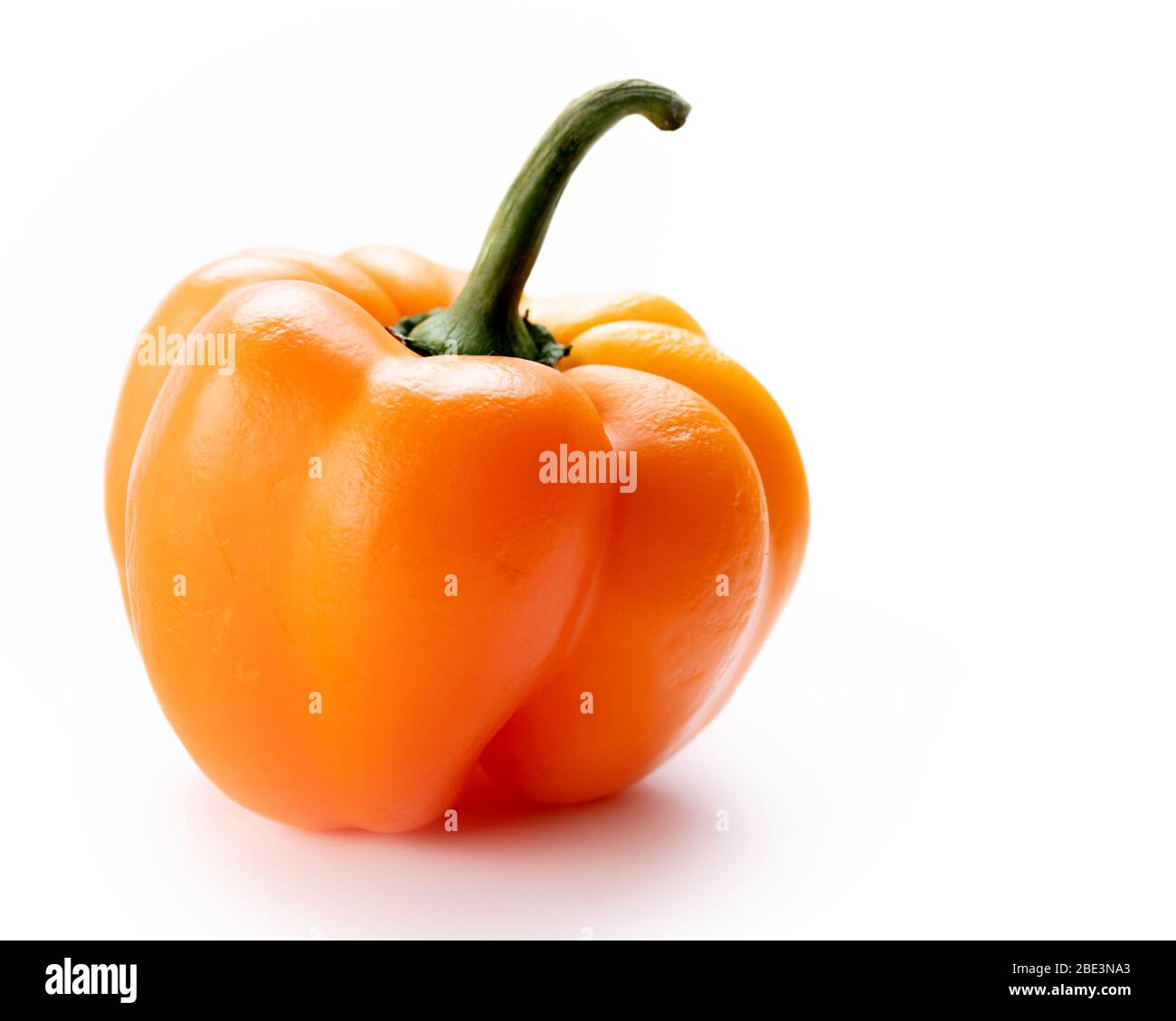 Fond blanc avec un poivron de cloche de couleur orange Banque D'Images