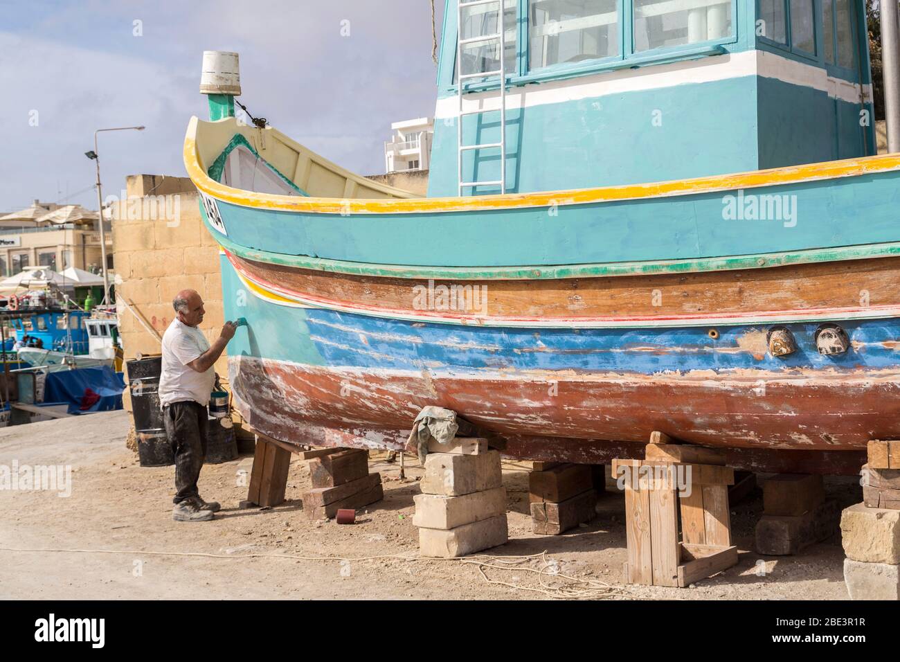 Repeindre un bateau de pêche traditionnel, Marsaxlokk, Malte Banque D'Images