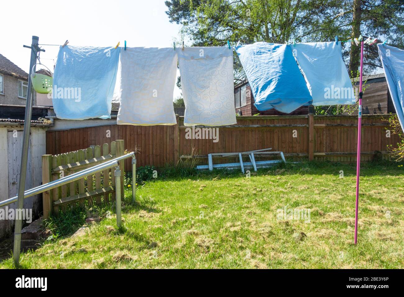 La literie et les draps sont fraîchement lavés et sont suspendus pour sécher sur une ligne de lavage dans le jardin résidentiel arrière. Banque D'Images