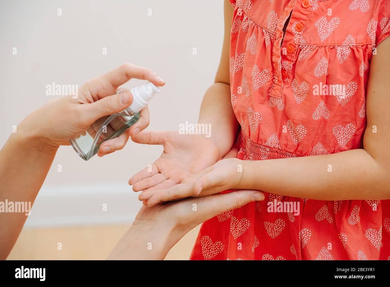 Maman utilise un spray antiseptique sur la paume de sa fille Banque D'Images