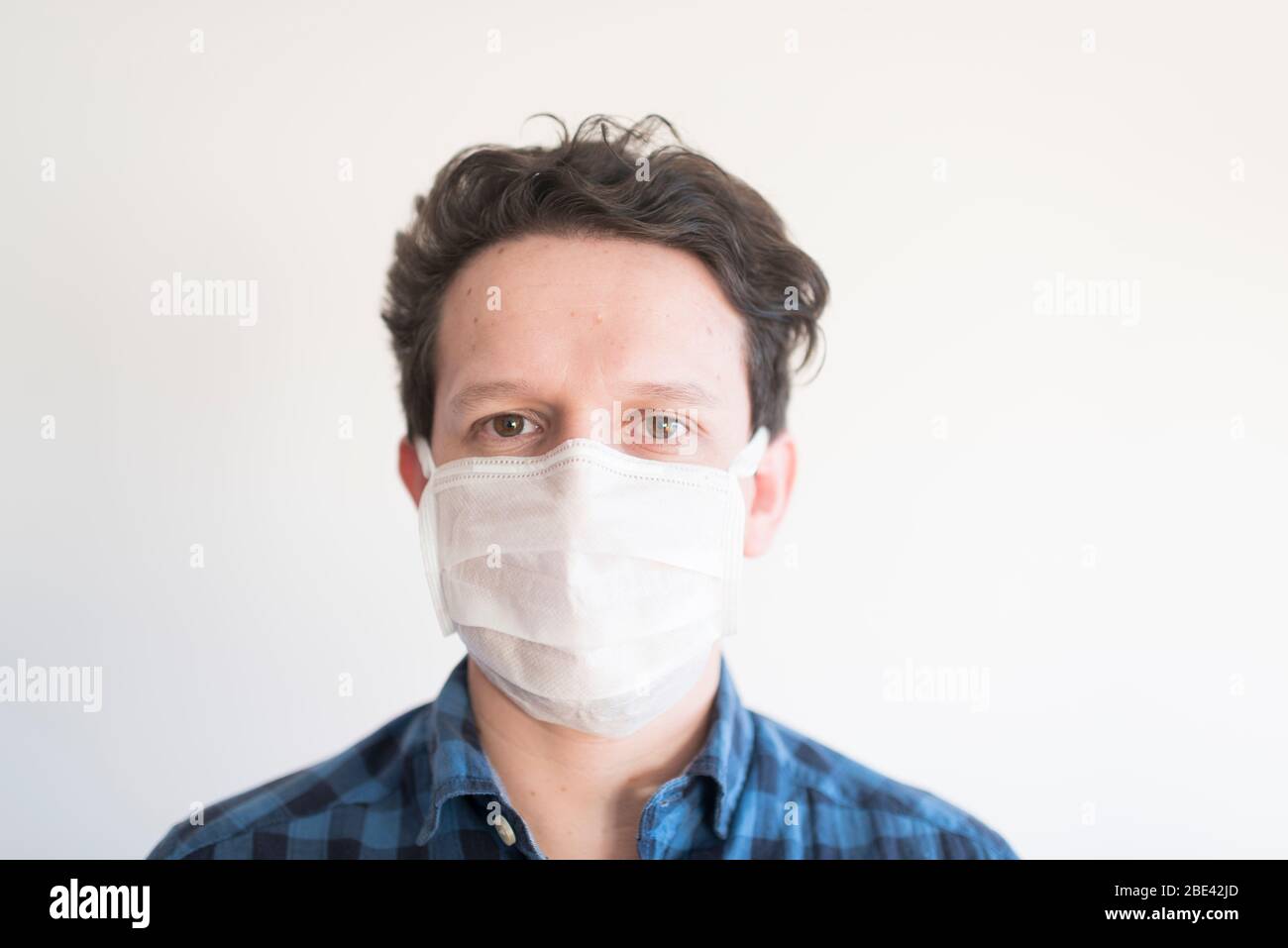 Portrait avant d'un jeune homme portant un masque facial jetable, pour empêcher la propagation de la maladie du coronavirus, Covid-19 Banque D'Images