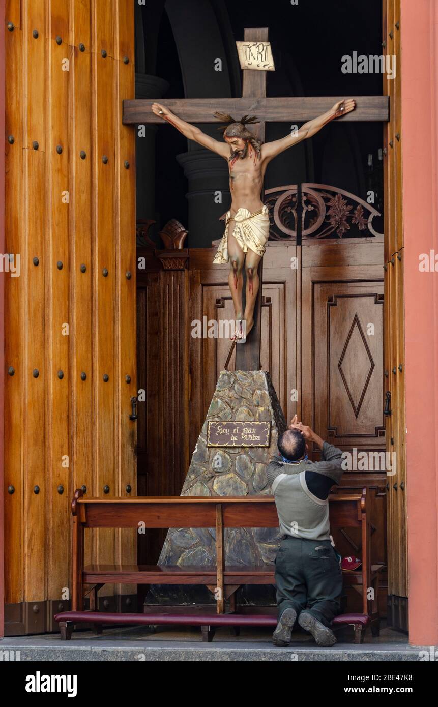 Un homme prie devant une image de Jésus-Christ crucifié dans une église de Caracas sur une semaine Sainte atypique en raison de la quarantaine par le Covid-19 Banque D'Images