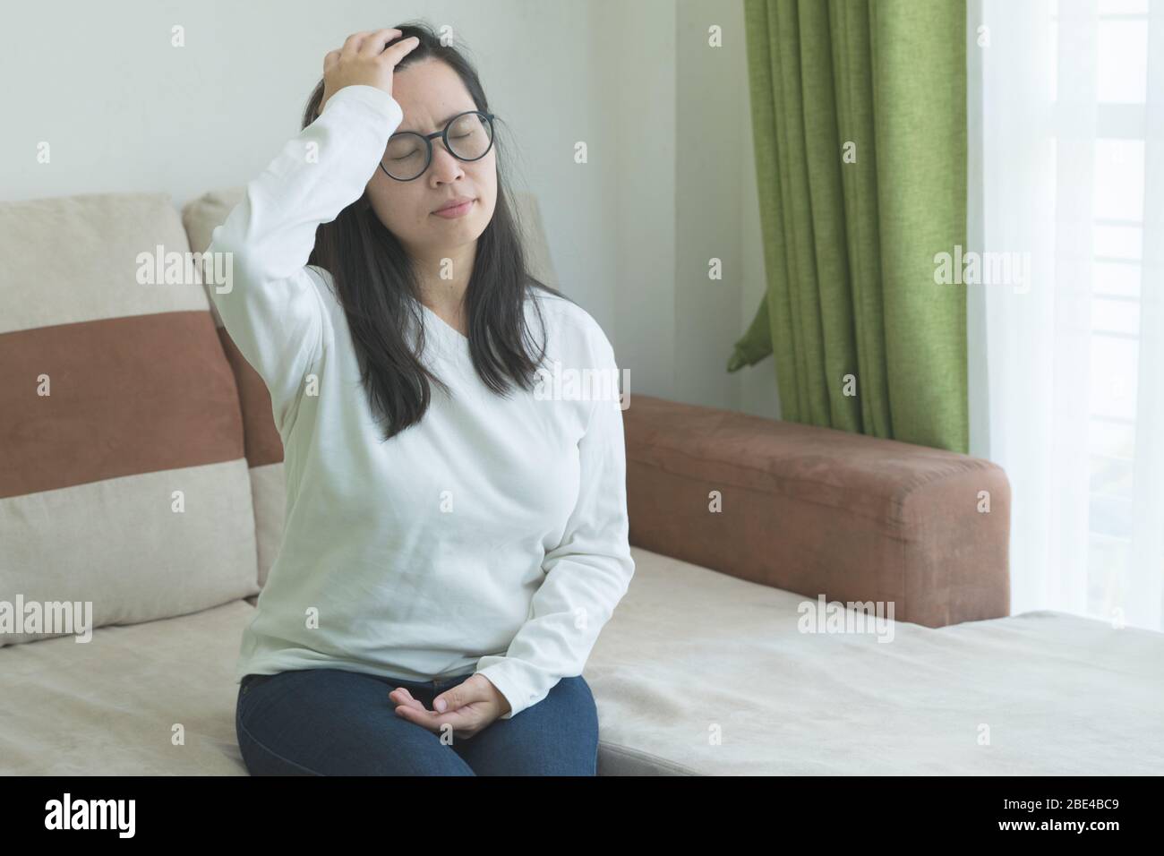 Jeune malin beau toucher sa tête à la main, mal de tête dans le fond de salon. Coronavirus(Covid-19). Banque D'Images