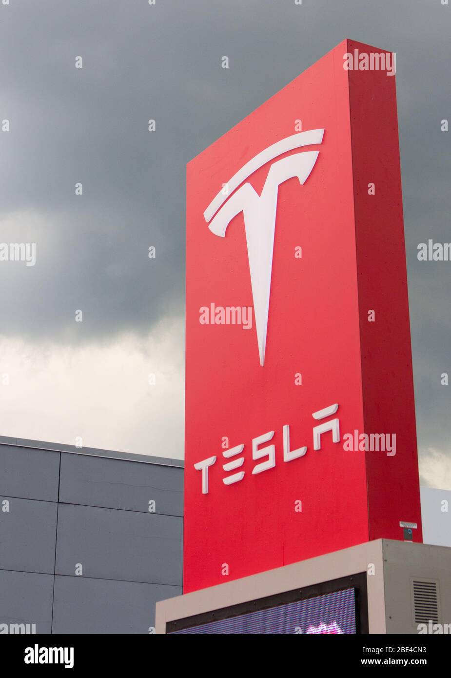 Enseigne de logo rouge et blanc de la compagnie de voiture électrique à l'extérieur du magasin Tesla Tysons Corner-Tyco Road, Vienne, Virginie, États-Unis, avec nuage de tempête de cumulonimbus au-dessus Banque D'Images