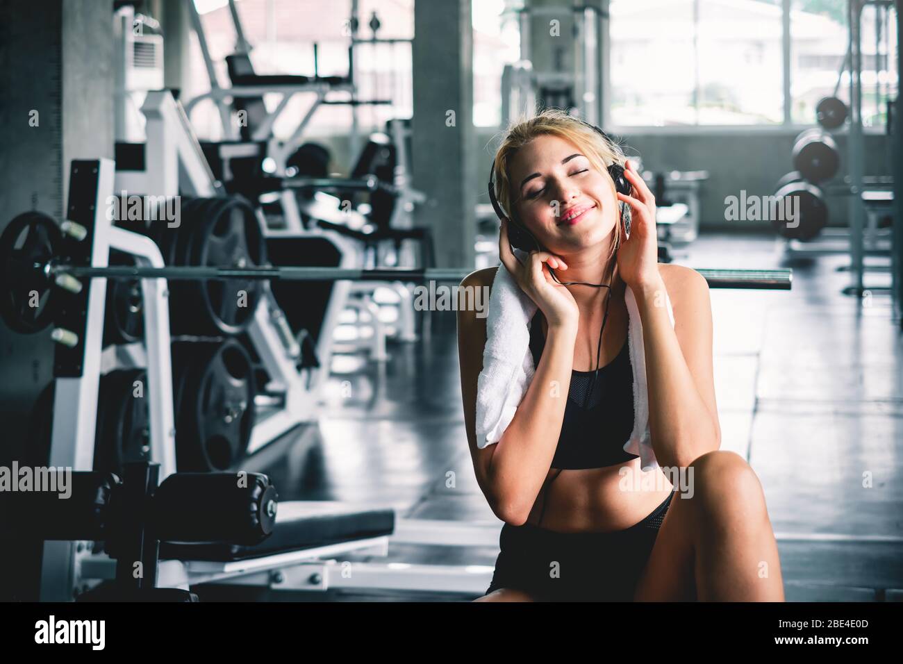 femme écoutant de la musique pendant l'entraînement et prendre un repos à la salle de sport pour se détendre avec plaisir et sourire Banque D'Images