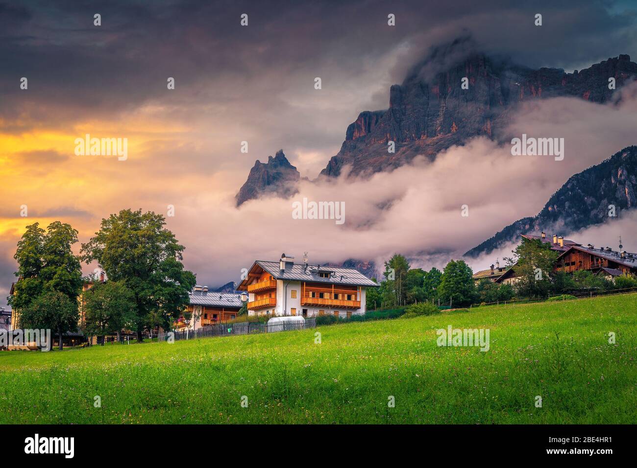 Charmant village alpin avec champs verts fleuris et montagnes brumeuses en arrière-plan au coucher du soleil, Dolomites, San Vito di Cadore, Italie, Europe Banque D'Images