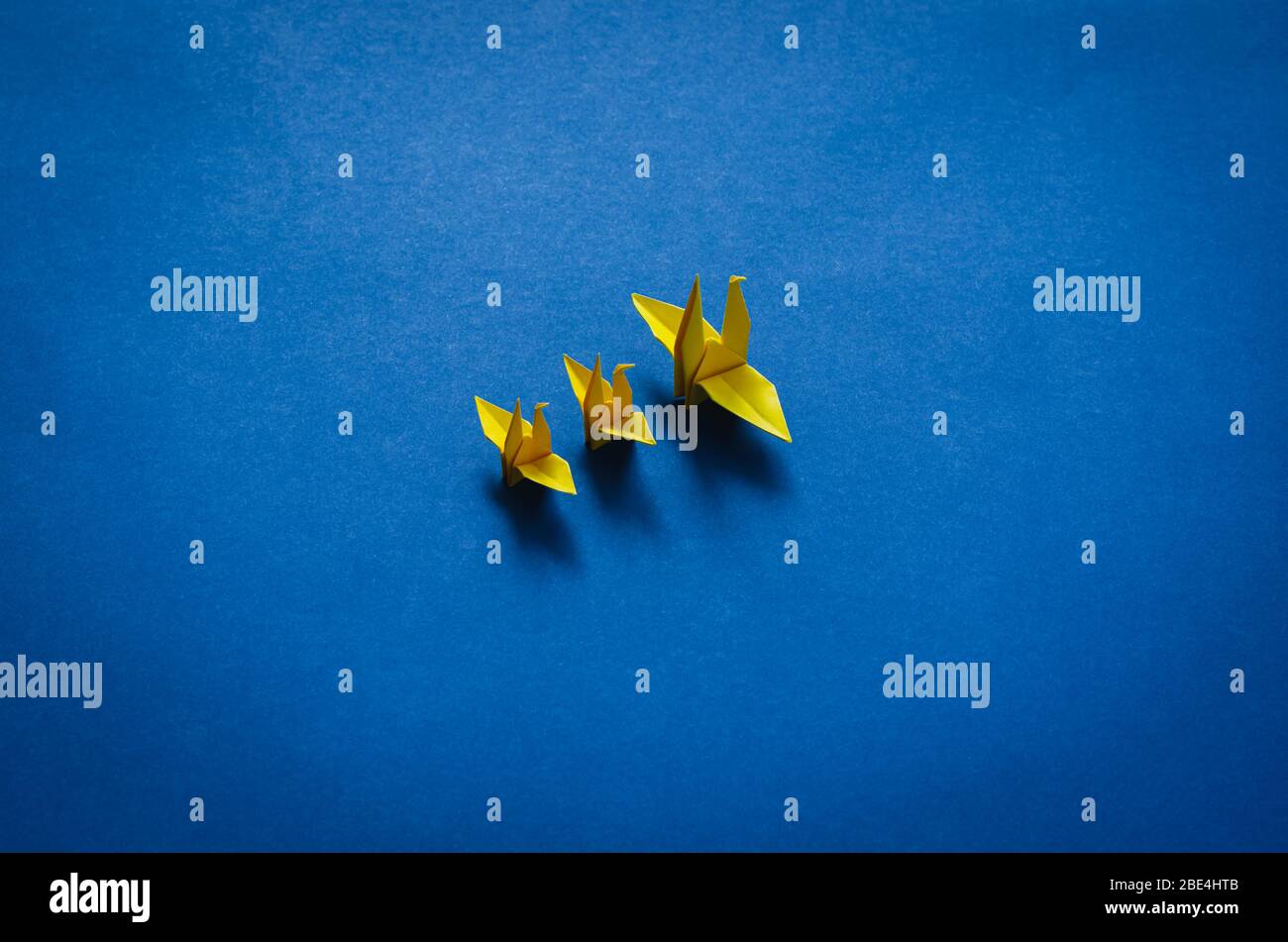 Papier jaune mère et bébé oiseaux sur fond bleu. Concept de la fête des mères minimale. Banque D'Images