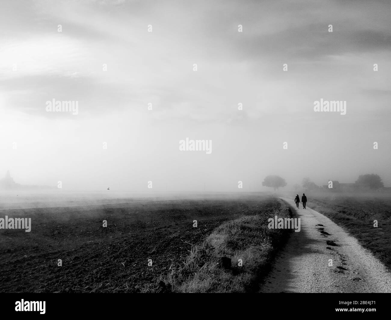 Vue sur le pays au milieu du brouillard avec un couple marchant sur une route Banque D'Images