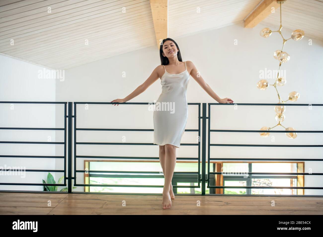 Jeune femme en soirée robe debout sur escalier avec les deux mains sur rails Banque D'Images