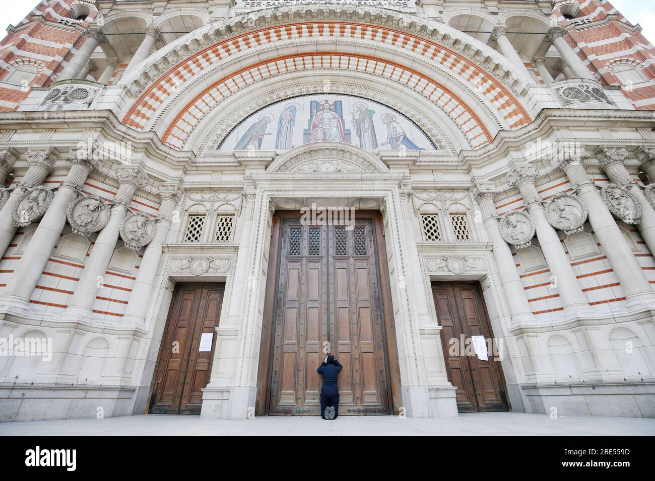 Une femme prie à la porte fermée de la cathédrale de Westminster devant la messe du matin de Pâques, Londres, alors que le Royaume-Uni continue de se verrouiller pour aider à freiner la propagation du coronavirus. Les églises de tout le pays continuent de diffuser des services numériques jusqu'à Pâques, avec plus de 1 000 direct régulièrement. Banque D'Images