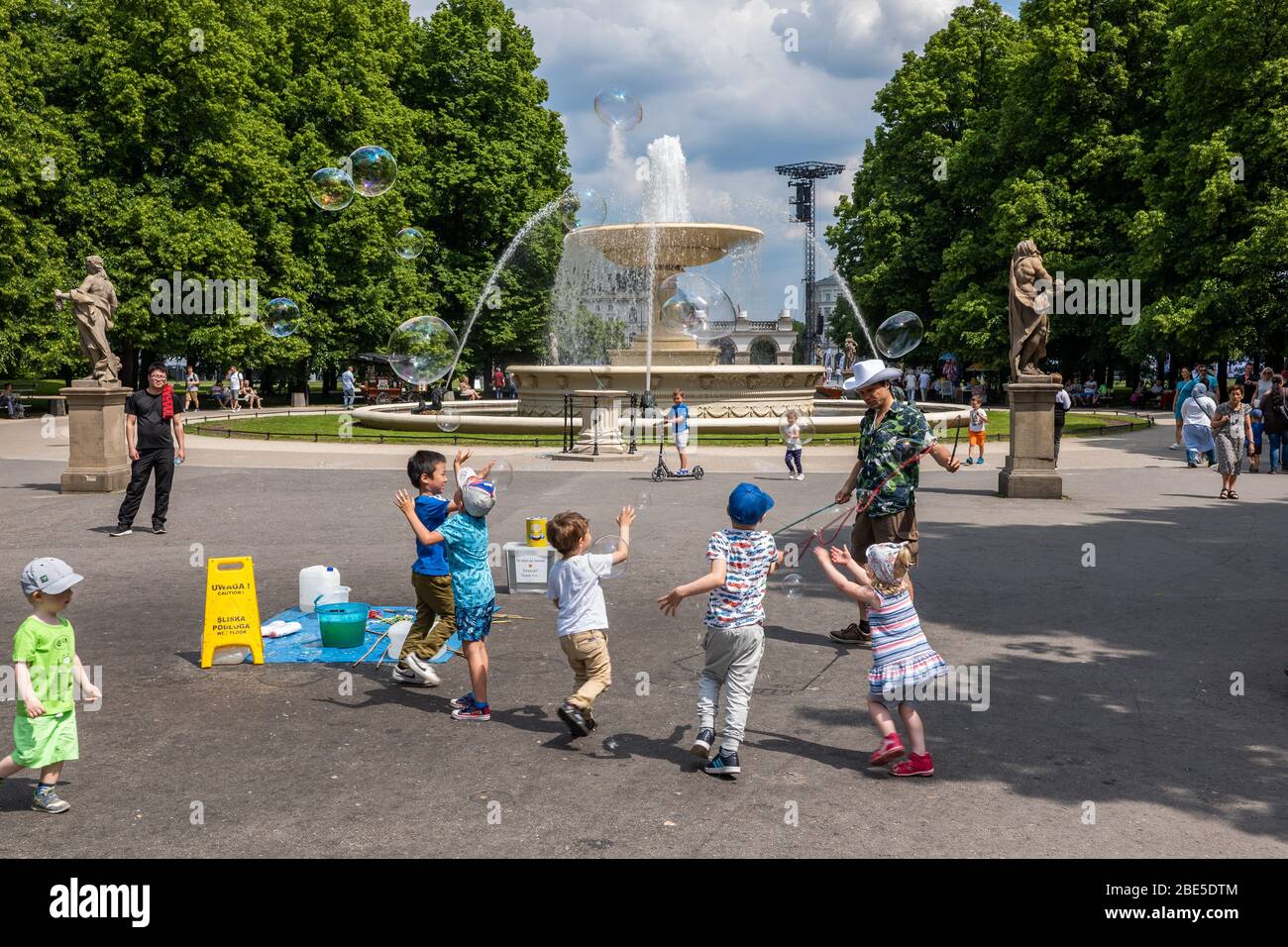 Saxon Garden dans la ville de Varsovie en Pologne, groupe d'enfants jouant avec des bulles de savon dans la place du parc avec fontaine en arrière-plan Banque D'Images