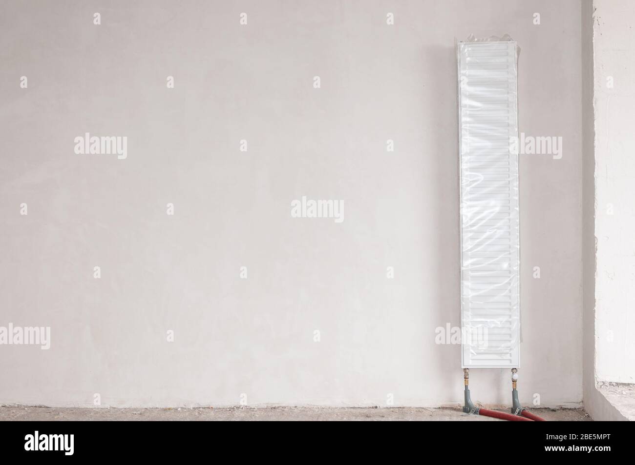 Un radiateur de chauffage monté verticalement dans une nouvelle maison. Nouveau bâtiment. Travaux préparatoires à la construction d'un nouveau bâtiment. Banque D'Images