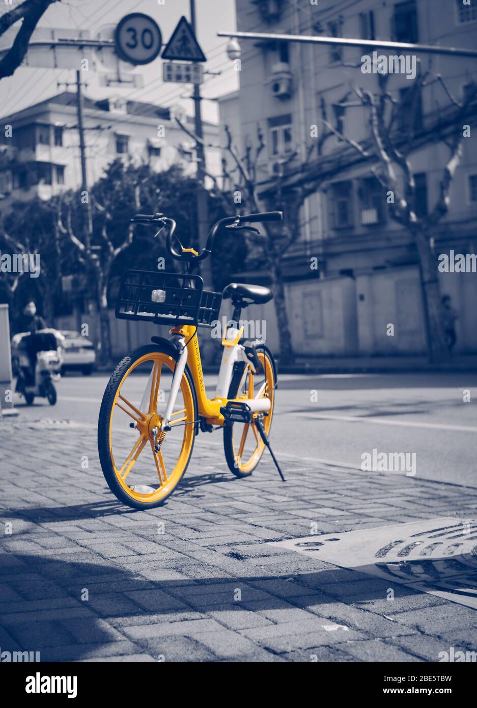 Vélo jaune dans une rue avec fond noir et blanc Banque D'Images