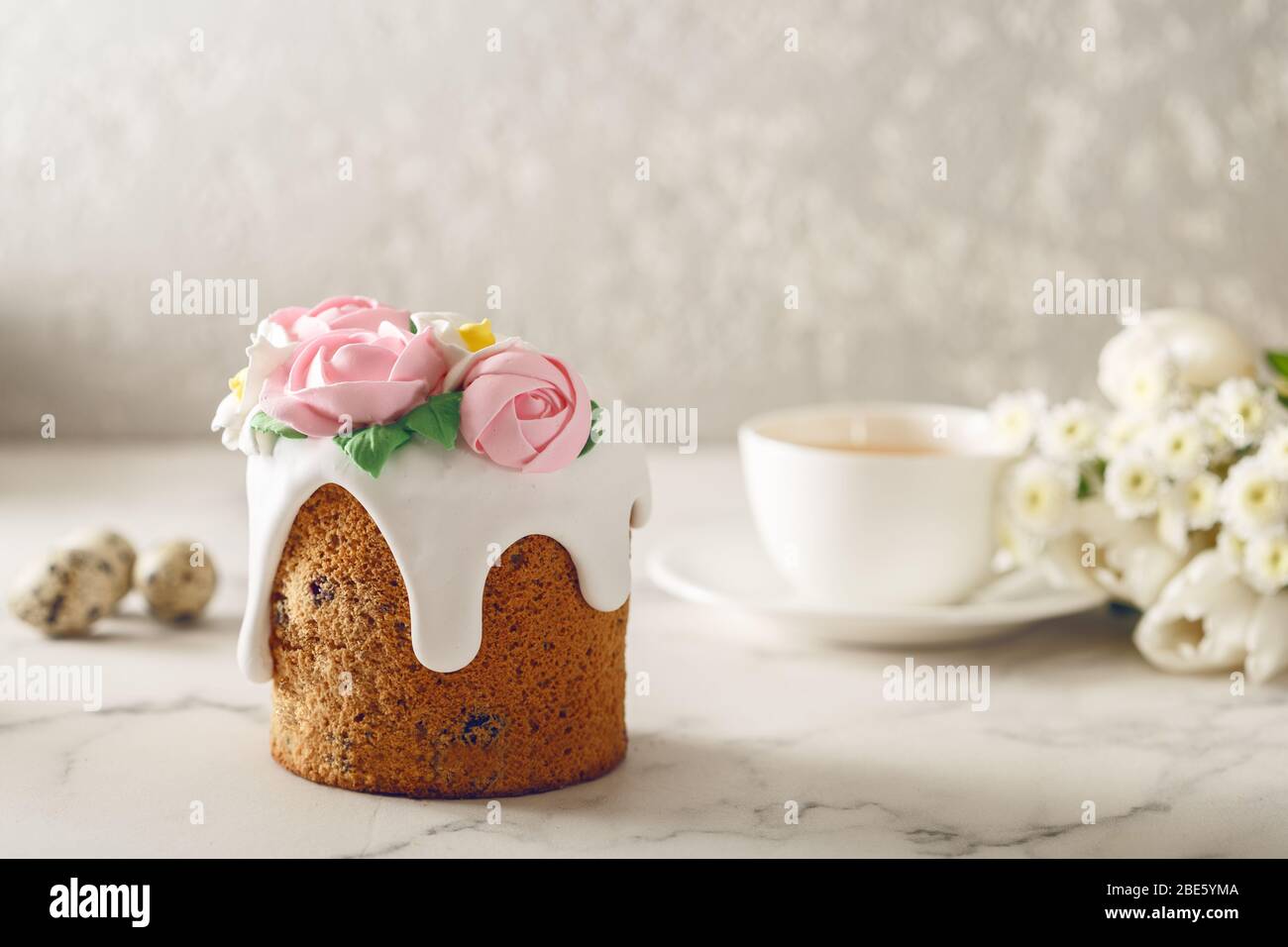 Petit déjeuner de Pâques. Gâteau maison avec crème coulante et roses roses sur table en marbre. Tasse de thé avec fleurs. Concept de vacances Banque D'Images