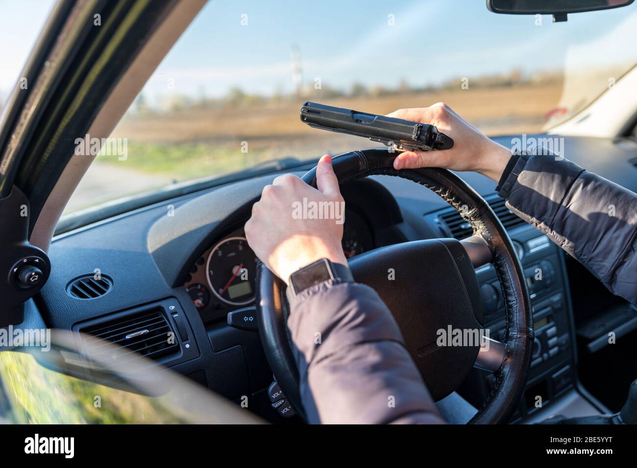 jeune homme avec pistolet en main dans la voiture de passager sur le siège du conducteur Banque D'Images