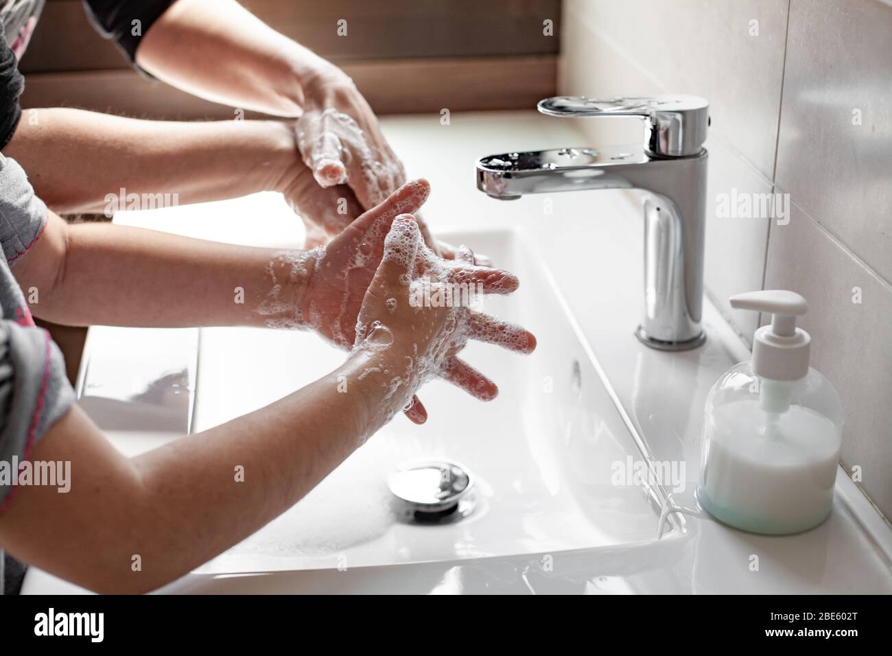 Mère enseignant à sa fille comment se laver correctement les mains avec du savon pour prévenir l'infection du coronavirus Banque D'Images