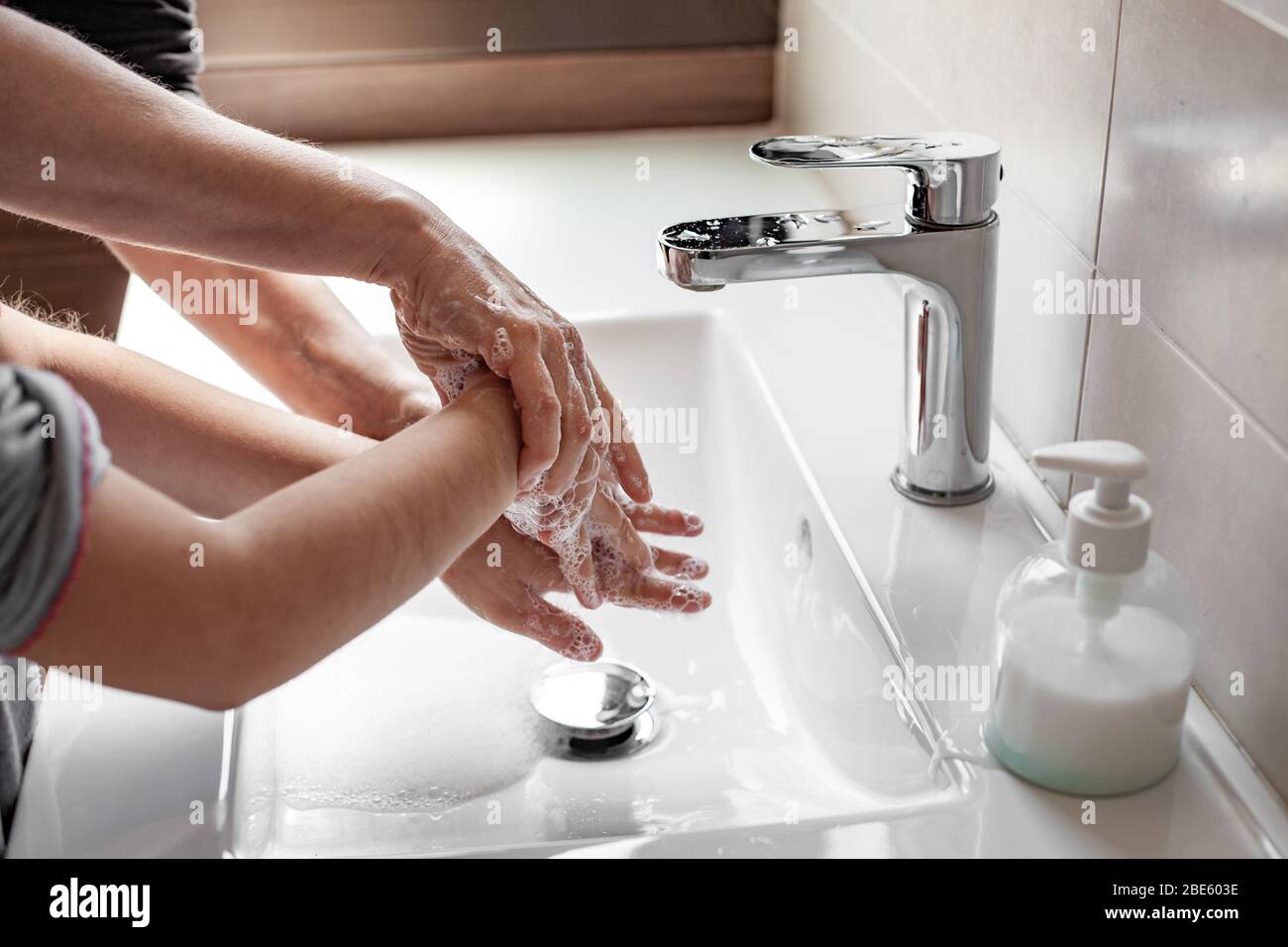 Mère enseignant à sa fille comment se laver correctement les mains avec du savon pour prévenir l'infection du coronavirus Banque D'Images