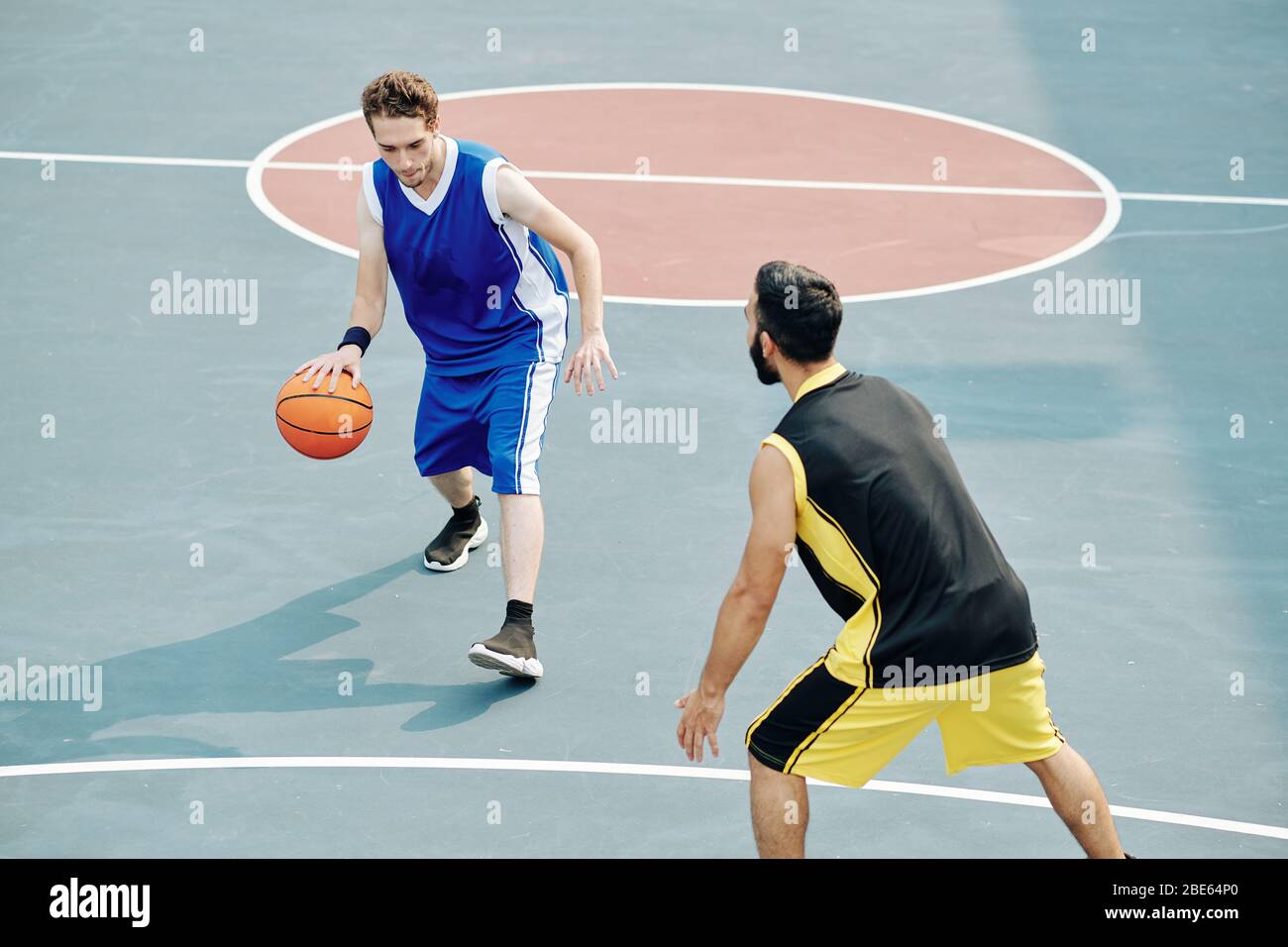 Amis en uniforme de sport jouant au basket-ball sur un terrain de plein air Banque D'Images