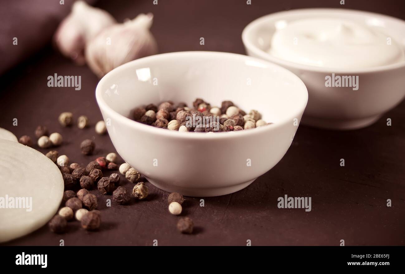 Poivrons rouges, noirs, blancs dans un petit bol blanc Banque D'Images