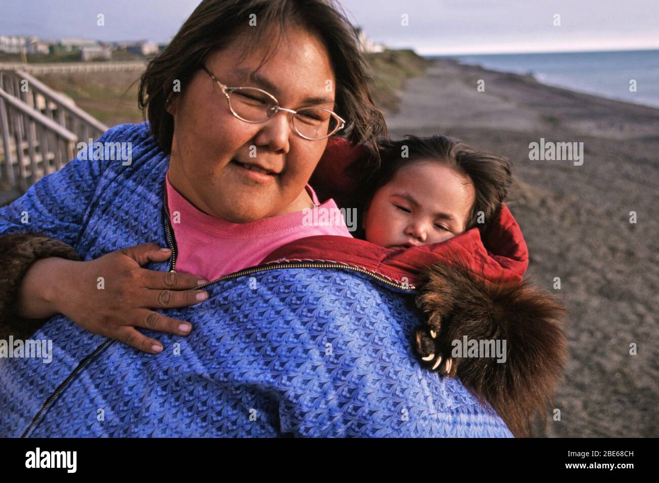 Inupiaq Inuit femme avec bébé en papose et tout-petit dans des vestes assorties sur le rivage de l'océan Arctique à 22:00 la nuit, Barrow, Alaska, États-Unis. Banque D'Images