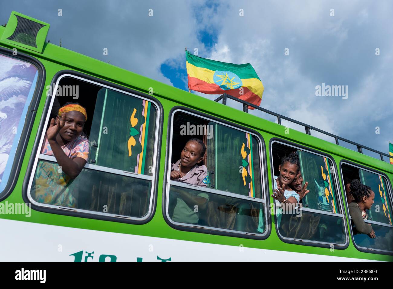 Les élèves de l'école se délaissent des fenêtres de bus pendant que la procession des élèves arrive à Jenka pour commencer le nouveau terme scolaire, Jenka, Ethiopie, Afrique. Banque D'Images