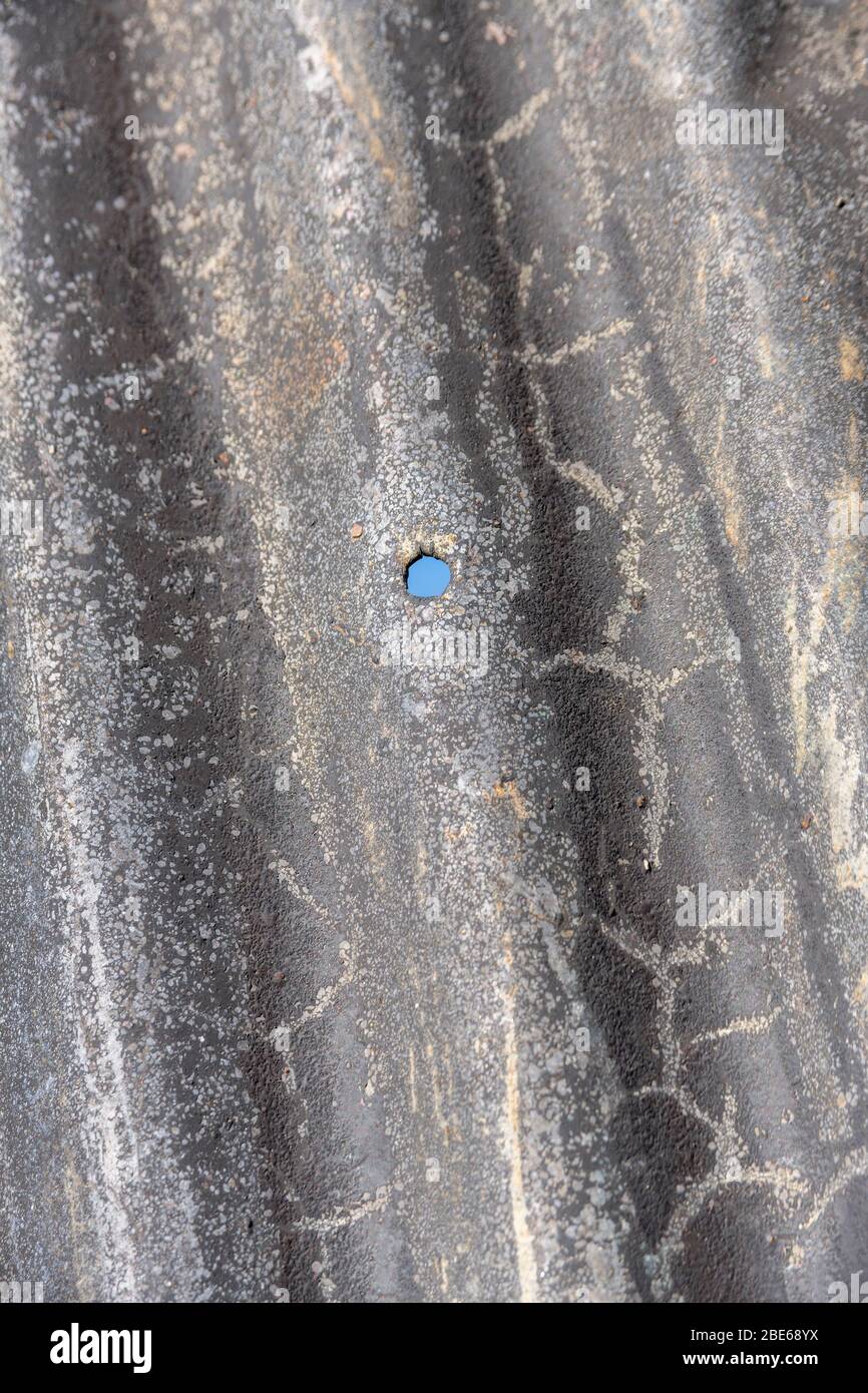 Tôle d'acier ondulé qui a vu de meilleurs jours et trou de boulon de fixation. Banque D'Images