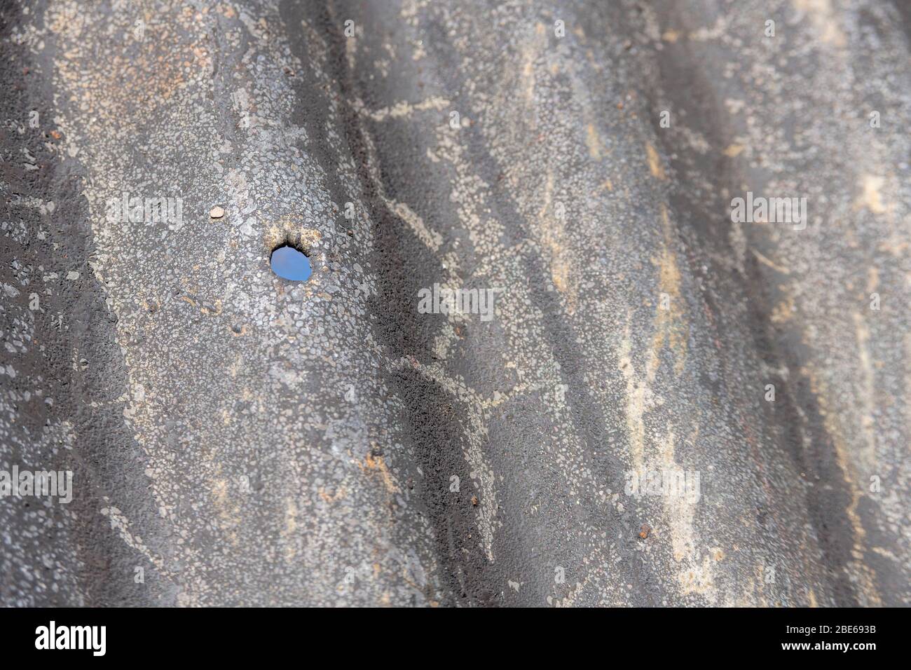 Tôle d'acier ondulé qui a vu de meilleurs jours et trou de boulon de fixation. Banque D'Images