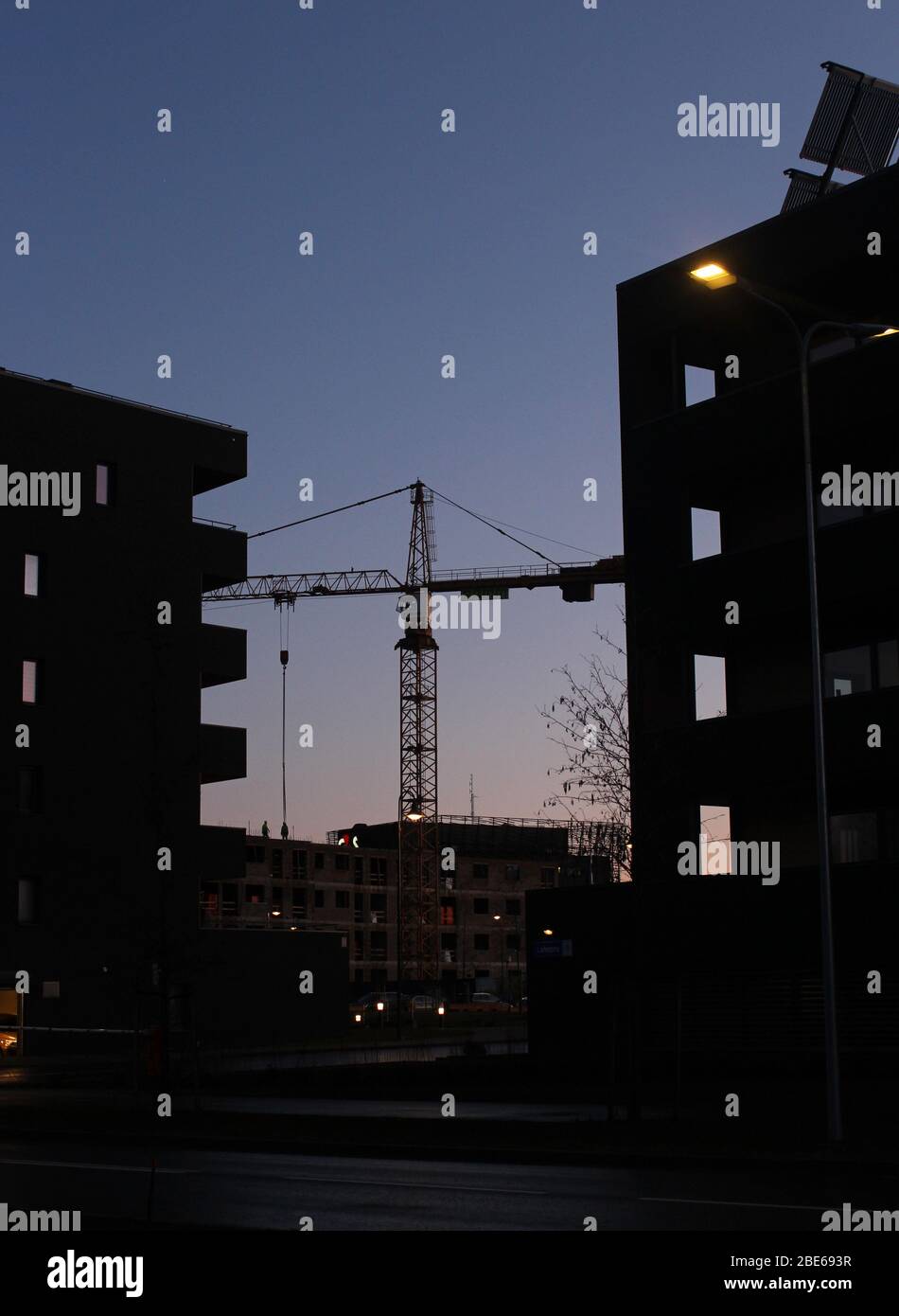 Silhouette d'un bâtiment en construction de nuit avec une grue Banque D'Images