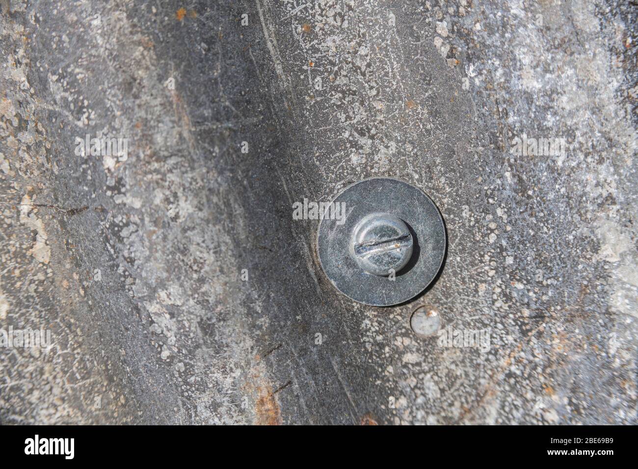 Tôle d'acier ondulé qui a vu de meilleurs jours et tête de boulon de fixation avec rondelle métallique. Banque D'Images